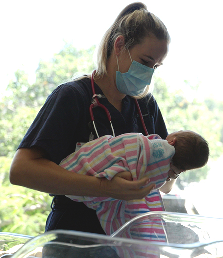 A midwife, holding a baby