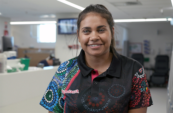 An Aboriginal woman in a medical setting, wearing a shirt printed with Aboriginal artwork.