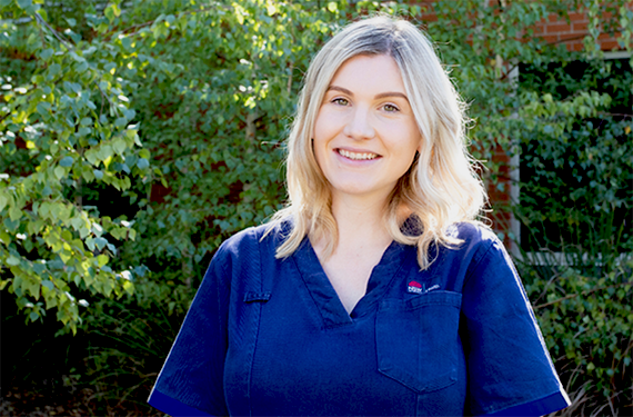 A blonde woman wearing a NSW Health nursing uniform standing outside