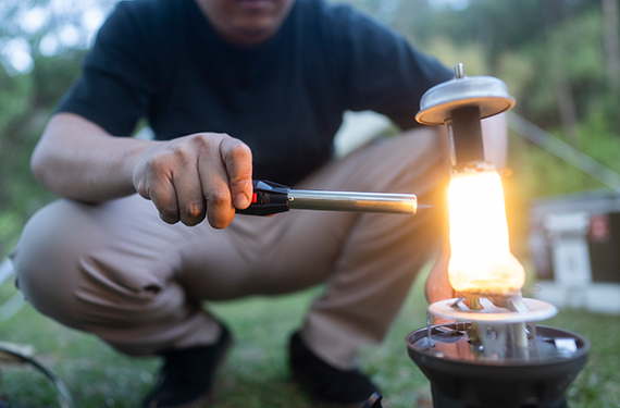 Friends chatting in tent at night while camping. The tent is closed and lit by a gas lantern.