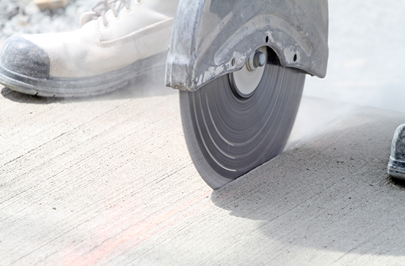 Close-up shot of a cutoff saw in action sawing expansion joints in newly constructed concrete.