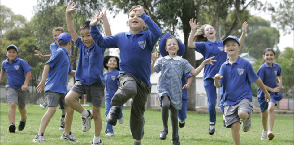 big crowd of children in school uniforms running and playing