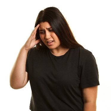 A student looking nervous. They are touching their hand to their forehead.