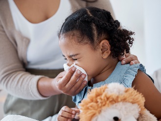 A parent using a tissue to blow a child's nose.