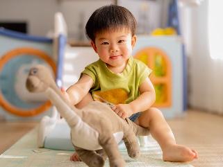 An 18 month old toddler playing with a dinosaur.