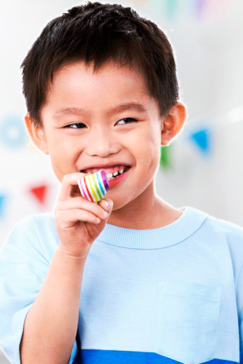 A young, smiling Asian boy with a party blower. 