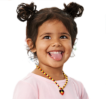 An Aboriginal girl with pigtails and an Aboriginal flag necklace, smiling and sticking out her tongue.