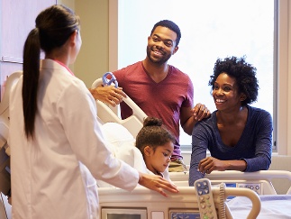 A doctor having a conversation with 2 family members who are visiting a child in hospital.