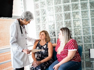 A doctor talking to a patient and another person seated next to them.