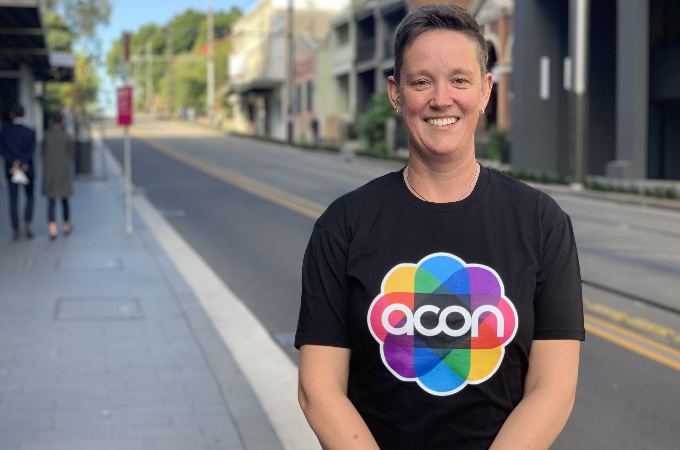 Qoman with short cropped hair in black T-shirt with words acon on it.