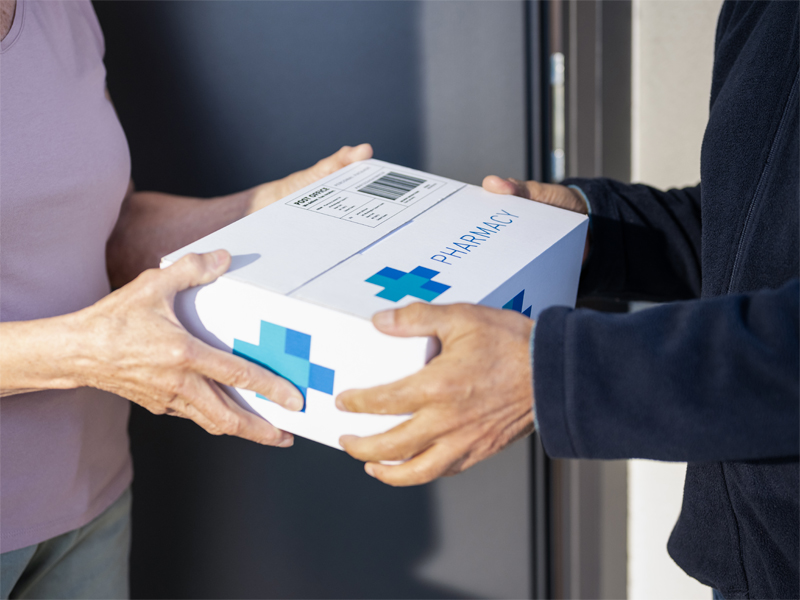 A person handing a pharmacy parcel to someone else.