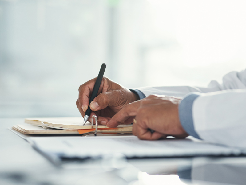 A doctor writing on a document.