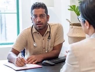 A doctor having a conversation with a patient. The doctor is writing down notes.