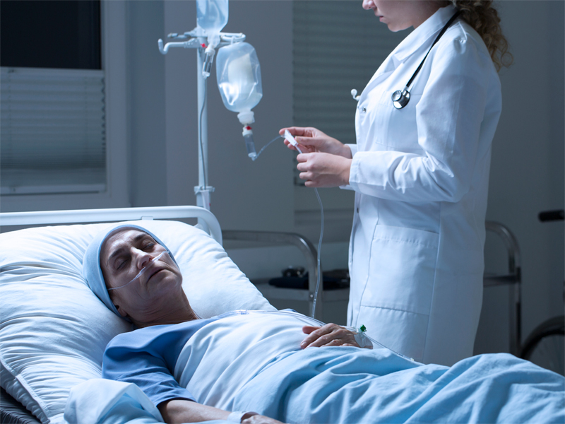 A person lying down in a medical bed. A doctor is caring for them.