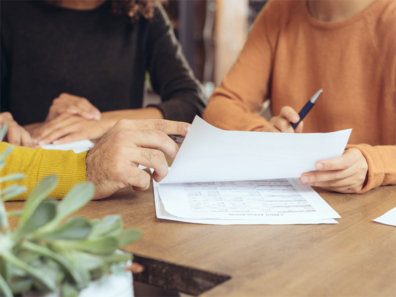 2 people supporting someone to sign a document.