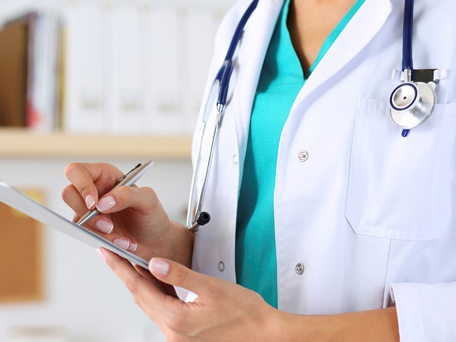 A doctor writing on a clipboard.