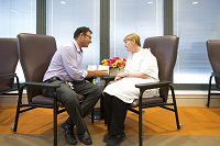 A social worker talking to a patient in a hospital gown.