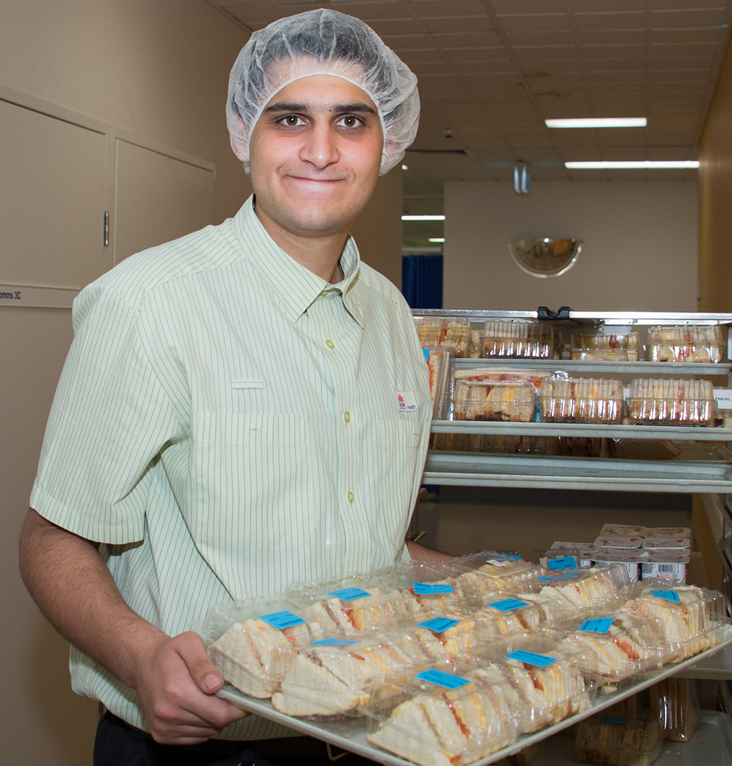 South Asian man holding a try of sandwiches